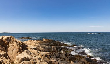 Sakin Bulgar deniz manzarası, sakin mavi yansıtıcı Karadeniz ve parlak güneşli akşam günbatımına karşı eski kayalık taşlar.