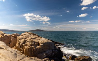 Sakin Bulgar deniz manzarası, sakin mavi yansıtıcı Karadeniz ve parlak güneşli akşam günbatımına karşı eski kayalık taşlar.