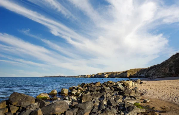 Sakin Bulgar deniz manzarası, sakin mavi yansıtıcı Karadeniz ve parlak güneşli akşam günbatımına karşı eski kayalık taşlar.