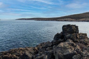 Sakin Bulgar deniz manzarası, sakin mavi yansıtıcı Karadeniz ve parlak güneşli akşam günbatımına karşı eski kayalık taşlar.