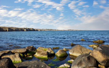 Sakin Bulgar deniz manzarası, sakin mavi yansıtıcı Karadeniz ve parlak güneşli akşam günbatımına karşı eski kayalık taşlar.
