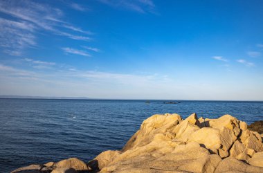 Sakin Bulgar deniz manzarası, sakin mavi yansıtıcı Karadeniz ve parlak güneşli akşam günbatımına karşı eski kayalık taşlar.