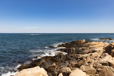 Sakin Bulgar deniz manzarası, sakin mavi yansıtıcı Karadeniz ve parlak güneşli akşam günbatımına karşı eski kayalık taşlar.