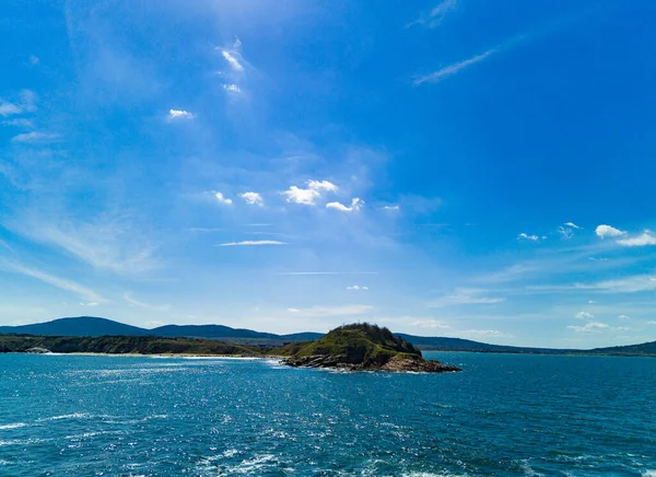 Vahşi bir taş ve kumlu sahil manzarası. Karanlık, nemli deniz kumları ve yansıtıcı yay yakınlarındaki kayalık kayalıklar. Karadeniz, Bulgaristan 'ın parlak, güneşli günbatımı ışığı altında.