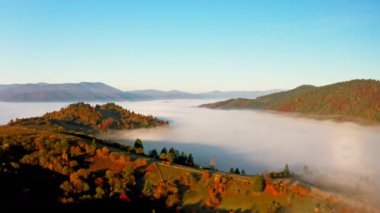 Dağları renkli ağaçlarla kaplayan kalın sis tabakası