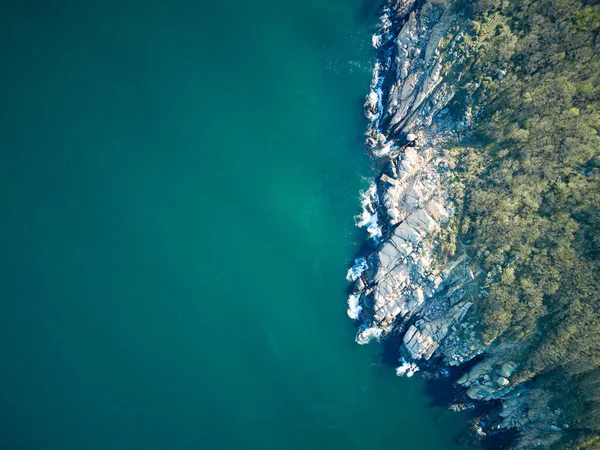 Vahşi bir taş ve kumlu sahil manzarası. Karanlık, nemli deniz kumları ve yansıtıcı yay yakınlarındaki kayalık kayalıklar. Karadeniz, Bulgaristan 'ın parlak, güneşli günbatımı ışığı altında.