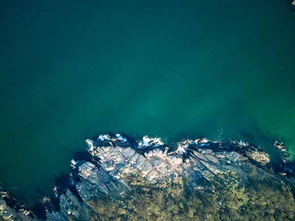 Vahşi bir taş ve kumlu sahil manzarası. Karanlık, nemli deniz kumları ve yansıtıcı yay yakınlarındaki kayalık kayalıklar. Karadeniz, Bulgaristan 'ın parlak, güneşli günbatımı ışığı altında.