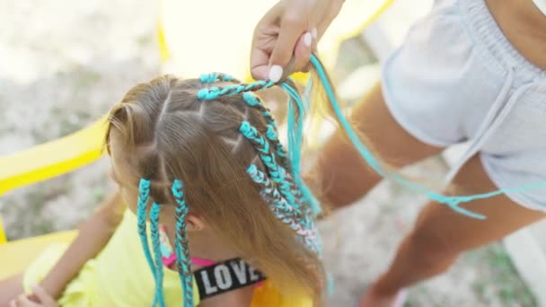 Девушка в костюме плетёт африканские косички в волосы в солнечный день — стоковое видео