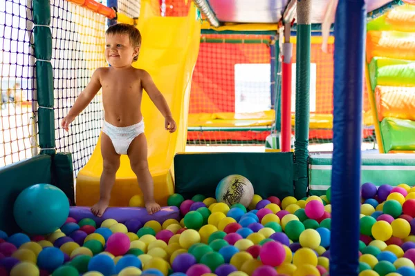 Дитина грає в ігровій кімнаті і котиться по слайду в басейн з маленькими кульками — стокове фото