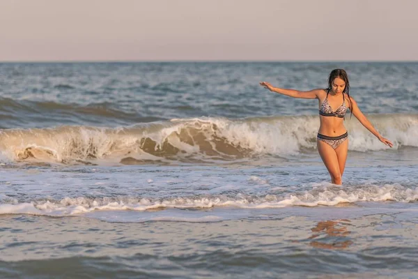 Saçları dökülmüş bir kız dalgalarla denizde yürüyor ve güneşin tadını çıkarıyor. — Stok fotoğraf