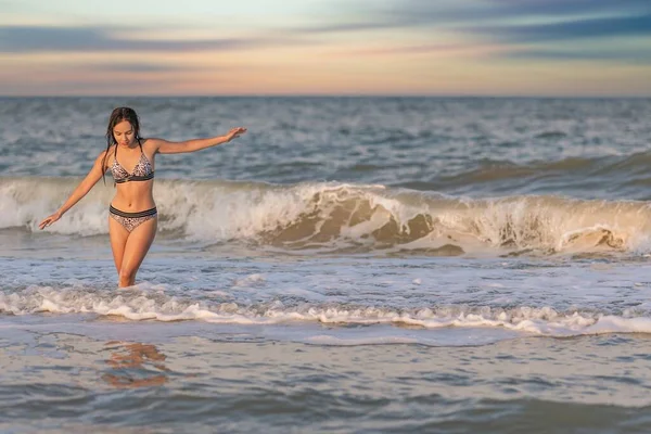 Ένα κορίτσι με χαλαρά μαλλιά περπατά στη θάλασσα με κύματα και απολαμβάνει τον ήλιο — Φωτογραφία Αρχείου