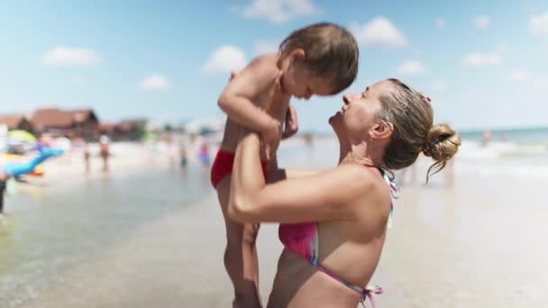母は息子を海の上に投げます夏休みに暖かい太陽の下で — ストック動画