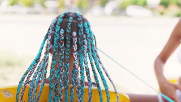 Dziewczyna w garniturze splata afrykańskie warkocze we włosach w słoneczny dzień — Wideo stockowe