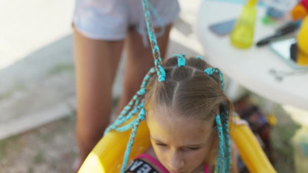 Dziewczyna w garniturze splata afrykańskie warkocze we włosach w słoneczny dzień — Wideo stockowe