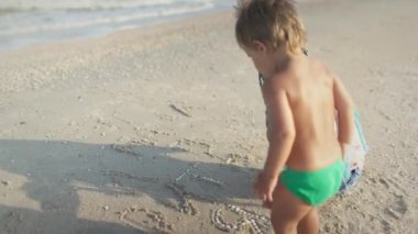 Büyük abla, yaz tatilinde küçük erkek kardeşiyle karaya oturmuş oynuyor.