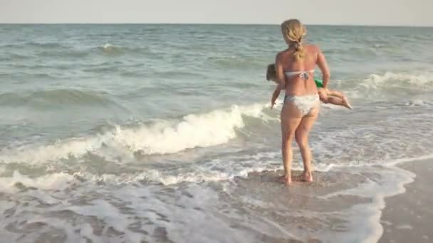 Maman jette son fils au-dessus de la mer en vacances d'été sous le soleil chaud — Video