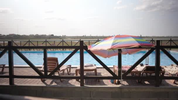 Sommarväder i semesterorten, solstrålarna skiner på solstolar med parasoller vid hotellpoolen — Stockvideo