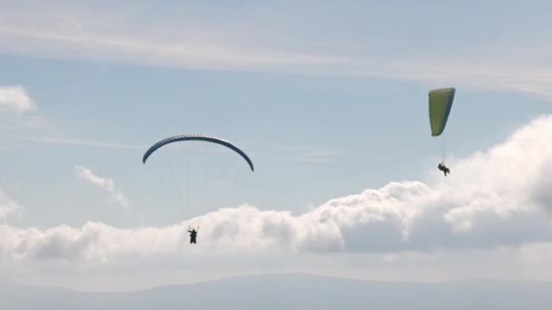Ludzie próbują paralotniarstwa ze spadochronami przeciwko chmurom. — Wideo stockowe