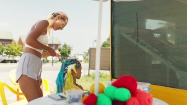Afrika örgüleri örgü ören bir kızın arka planına karşı masada bir sürü iplik ve kurdele var.