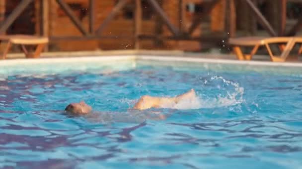 Жінка плаває в басейні з чистою водою на тлі літнього заходу сонця у відпустці — стокове відео