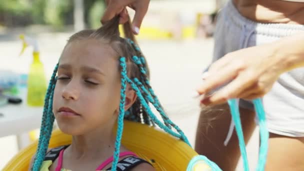 Una chica de traje teje trenzas africanas en su cabello en un día soleado — Vídeos de Stock