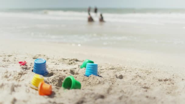 Muchos juguetes se encuentran en la playa cerca del mar bajo el sol de verano — Vídeos de Stock