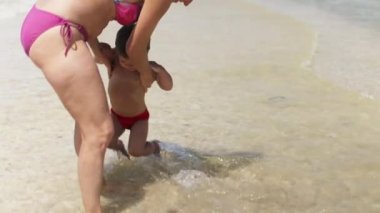 Anne oğlunu yaz tatilinde sıcak güneşin altında denize atıyor.