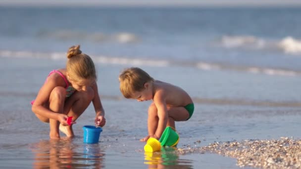 Older sister playing with younger brother aground near the shore on summer vacation — Stock Video