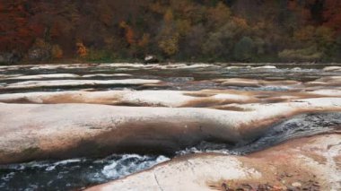 Kaydırıcı yavaş çekim videosu, nehir kıyılarda sonbahar ormanlarıyla birlikte akıntılar