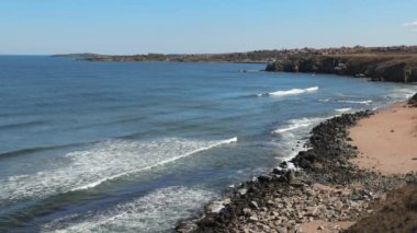 Uzakta otlarla ve otellerle kıyı açık bir gökyüzünün altında Karadeniz ile çevrili.