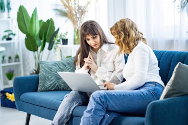 Tişörtlü iki kız telefona ve dairede bir dergiye bakarken bir şey tartışıyorlar.