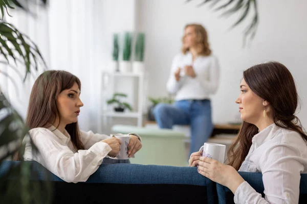 Três meninas discutem notícias e bebem chá no apartamento — Fotografia de Stock