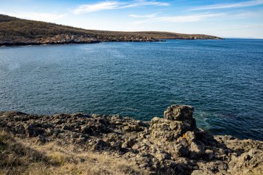 Sakin Bulgar deniz manzarası, sakin mavi yansıtıcı Karadeniz ve parlak güneşli akşam günbatımına karşı eski kayalık taşlar.