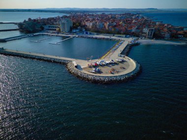 Birçok küçük eski beyaz tekne ve kayıklar bir taş üzerinde ve beton geniş rıhtım sakin mavi sakin Karadeniz yakınında, parlak, güneşli bir günbatımı ve bulutlu bir gökyüzü karşı