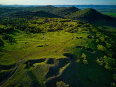 Bulgaristan 'da parlak bulutlu sıcak bir günün ışığı altında, Balkan Dağları' nın yeşil çayırları ve ormanlık yamaçlarına kuşbakışı bakmak