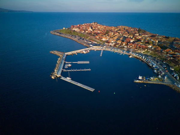 Bird\'s eye view of the small spring green town of Nessebar with historic ancient European houses and fresh blooming empty parks, washed by the calm porous deep Black Sea in Bulgaria