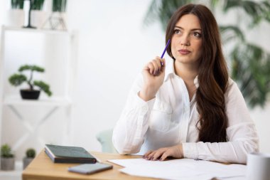 Koyu renk saçlı, beyaz, şık gömlekli, yaratıcı, hevesli bir kız bir masaya oturur ve defterine çizer ya da günlüğüne, rahat, aydınlık odasına notlar yazar.