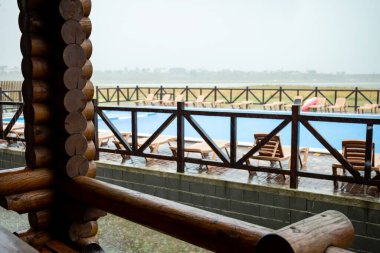 Büyük, nemli bir yaz yağmuru, bulutlu bir yaz gününde, büyük, mavi bir havuzun ve etrafındaki her şeyin üzerine yağar.