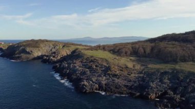 Bulgaristan 'ın parlak güneşli akşam günbatımına karşı sakin, mavi yansıtıcı Karadeniz ve eski karanlık kayalık taşlarla kaplı deniz manzarası. UHD 4K video gerçek zamanlı