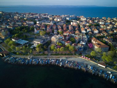 Bulgaristan 'ın Pomorie kentindeki antik tatil beldesi Pomorie' nin arka planında, bulutlu, mavi bir gökyüzü altında, derin ve sakin Karadeniz kıyısında yürüyen insanlarla deniz gezintisi.