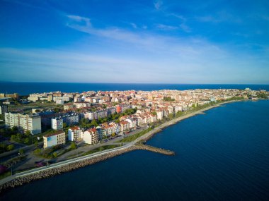 Bulgaristan 'ın Pomorie kentindeki antik tatil beldesi Pomorie' nin arka planında, bulutlu, mavi bir gökyüzü altında, derin ve sakin Karadeniz kıyısında yürüyen insanlarla deniz gezintisi.
