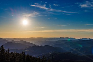 Dağ sıraları ile uçsuz bucaksız sisli dağ vadisi karanlık yeşil ladin ormanları ve Rodop Dağları 'ndaki dağ bitkilerinin koruduğu muhteşem güneşli akşam gökyüzünün zeminine karşı.