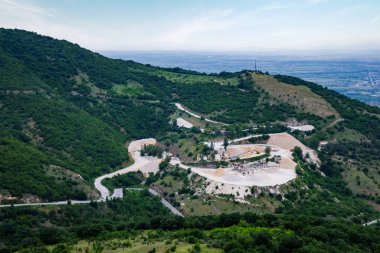 Profesyonel ekipman ve makinelerle mineralleri ve kumu çıkarmak için endüstriyel taş ocağı ve Rodop Dağları 'nda kozalaklı ormanlarla kaplı, etrafından geçen dağlar arası dolambaçlı yol.