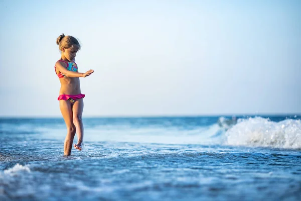 小さな波で遊んで面白い細い陽気な女の子 足を蹴り 暖かい明るい夏の太陽の下で所定の位置に回転待望の休暇を楽しんで — ストック写真