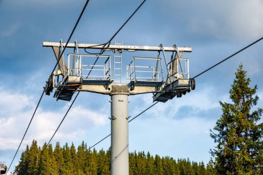 Güçlü ve güvenilir metal kablolu modern turist asansörü, Rodop Dağları 'nın dağ sıralarının arka planında, uzun tüylü, dikenli köknar ağaçlarıyla sonsuz yeşil ladin bahar ormanlarının arasından geçer.