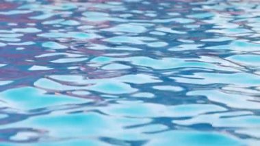 Büyük mavi bir havuzda, açık mavi bir su ve güneşin yansımaları. 4K UHD yavaş çekim videosu