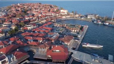 Bulgaristan 'ın Karadeniz kıyısındaki deniz manzarasına karşı yarımadada eski şirin evleri ve sakin bahar caddeleri olan antik tarihi Nesebar kasabasına kuşların bakış açısı. UHD 4K video gerçek zamanlı