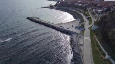 Bulgaristan 'ın Karadeniz kıyısındaki bir yarımadada yürüyen insanlarla dolu yeşil yay parkları ve dar caddelerle kaplı antik deniz kasabası Nesebar' a kuşların bakış açısı. UHD 4K video gerçek zamanlı