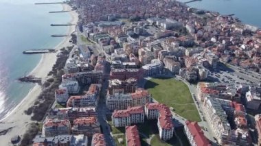 Bulgaristan 'ın kayalık yarımadasında bulunan ve büyük mavi, tuzlu Karadeniz tarafından turlanan küçük ve yoğun nüfuslu Pomorie kasabasına kuş bakışı bir bakış. UHD 4K video gerçek zamanlı