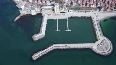 Küçük, yeni inşa edilmiş bir tatil köyünün kuş bakışı manzarası - Pomorie yarımadası, büyük, tuzlu, sakin Karadeniz 'de birçok farklı modern tekne ve tekne. UHD 4K video gerçek zamanlı